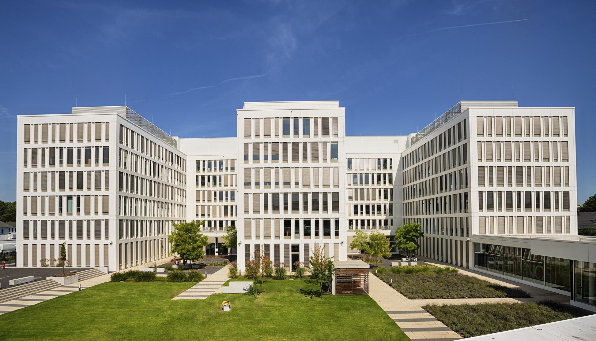 Büroensemble mit begrüntem Außenbereich unter blauem Himmel